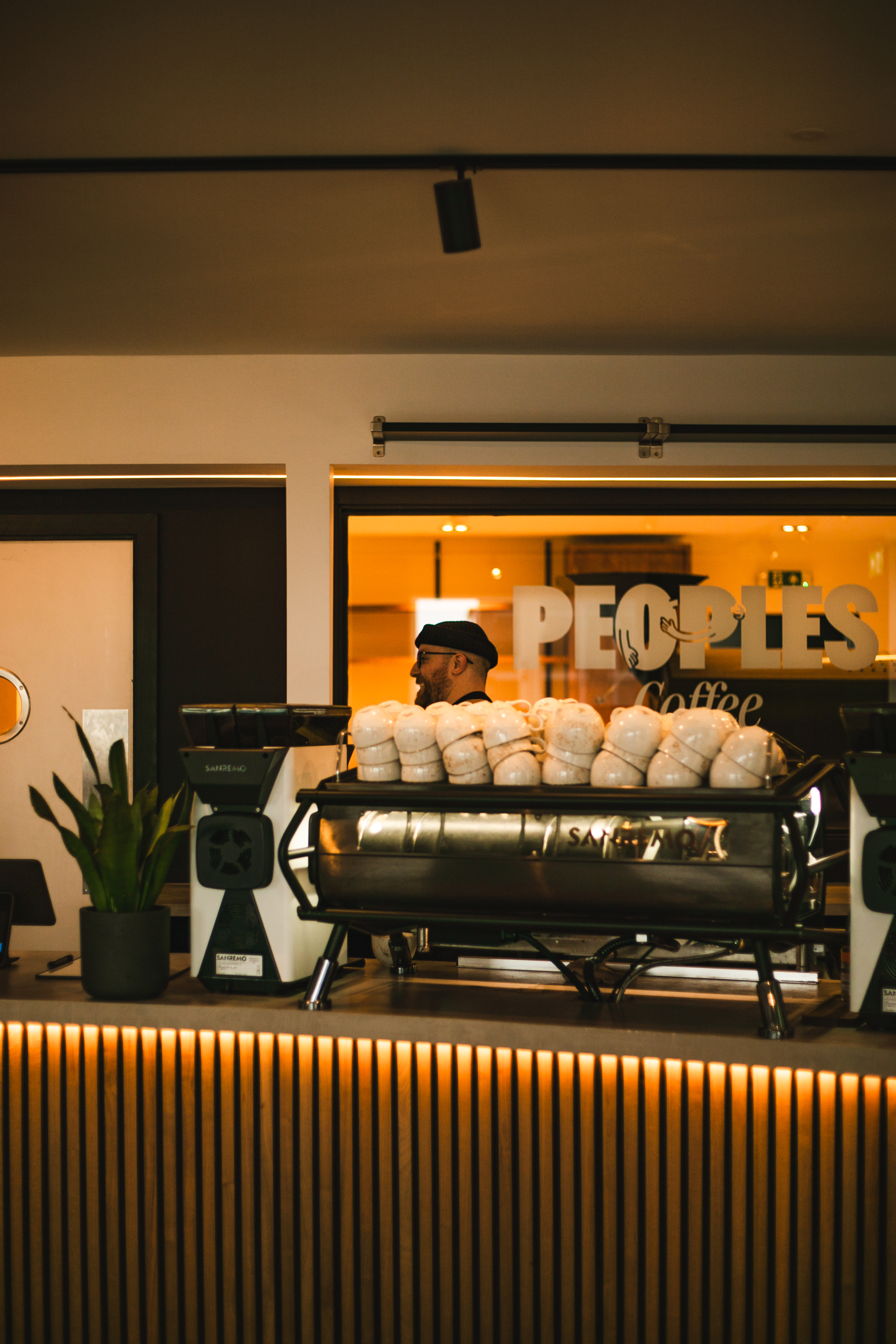 Barista at the Sanremo under the Peoples Coffee sign